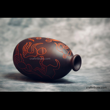 Handcrafted Terracotta Black Vase with free hand paintings lying horizontally on the ground.