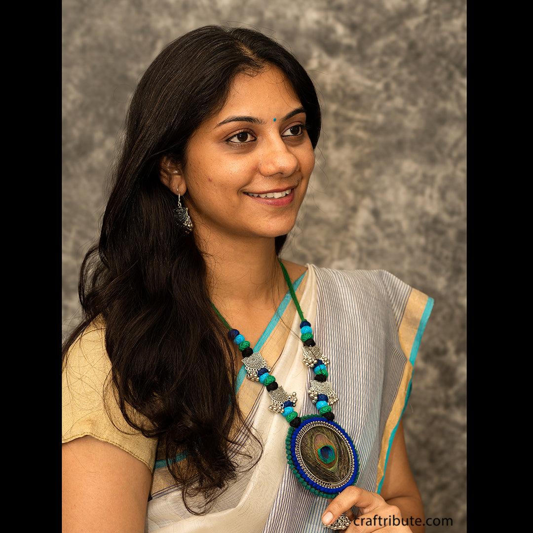 A lady wearing a white Chanderi saree with attractive jewelry, with a peacock feather