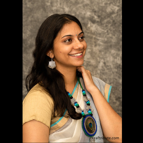 A lady wearing a silver earrings and necklace with cotton beads and silver pendants
