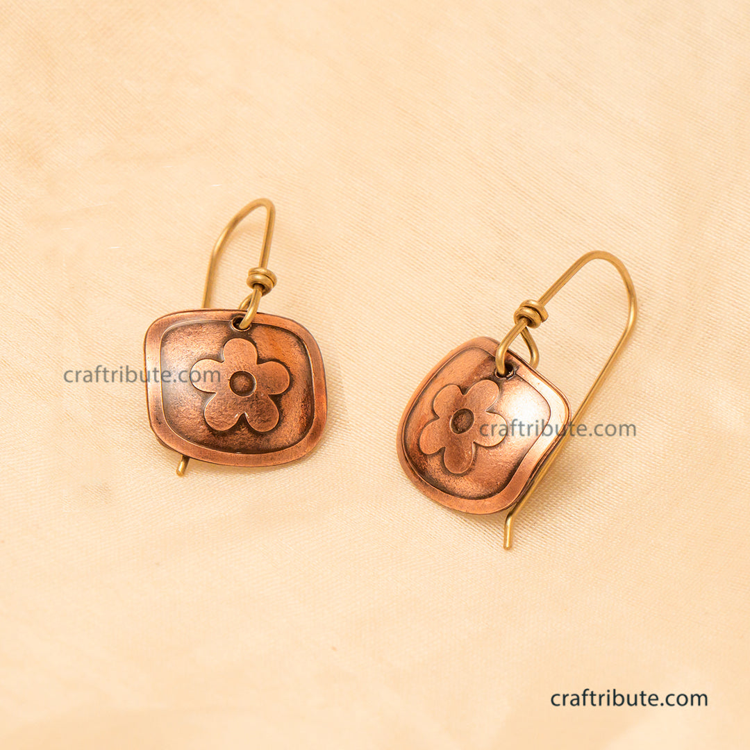 Handcrafted Copper Earrings with beautiful floral design placed on the beige silk background