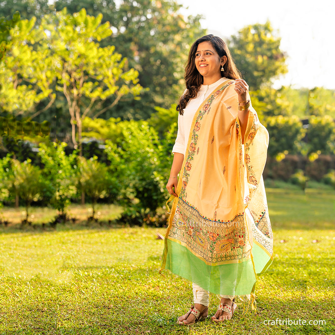 Girl wearing a cotton silk hand painted Madhubani dupatta with peacocks design having a green border.