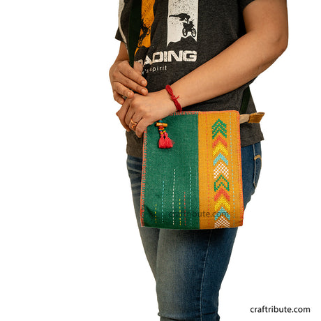 Model carrying a hand embroidered Yellow & Green jute sling bag with dark green belt