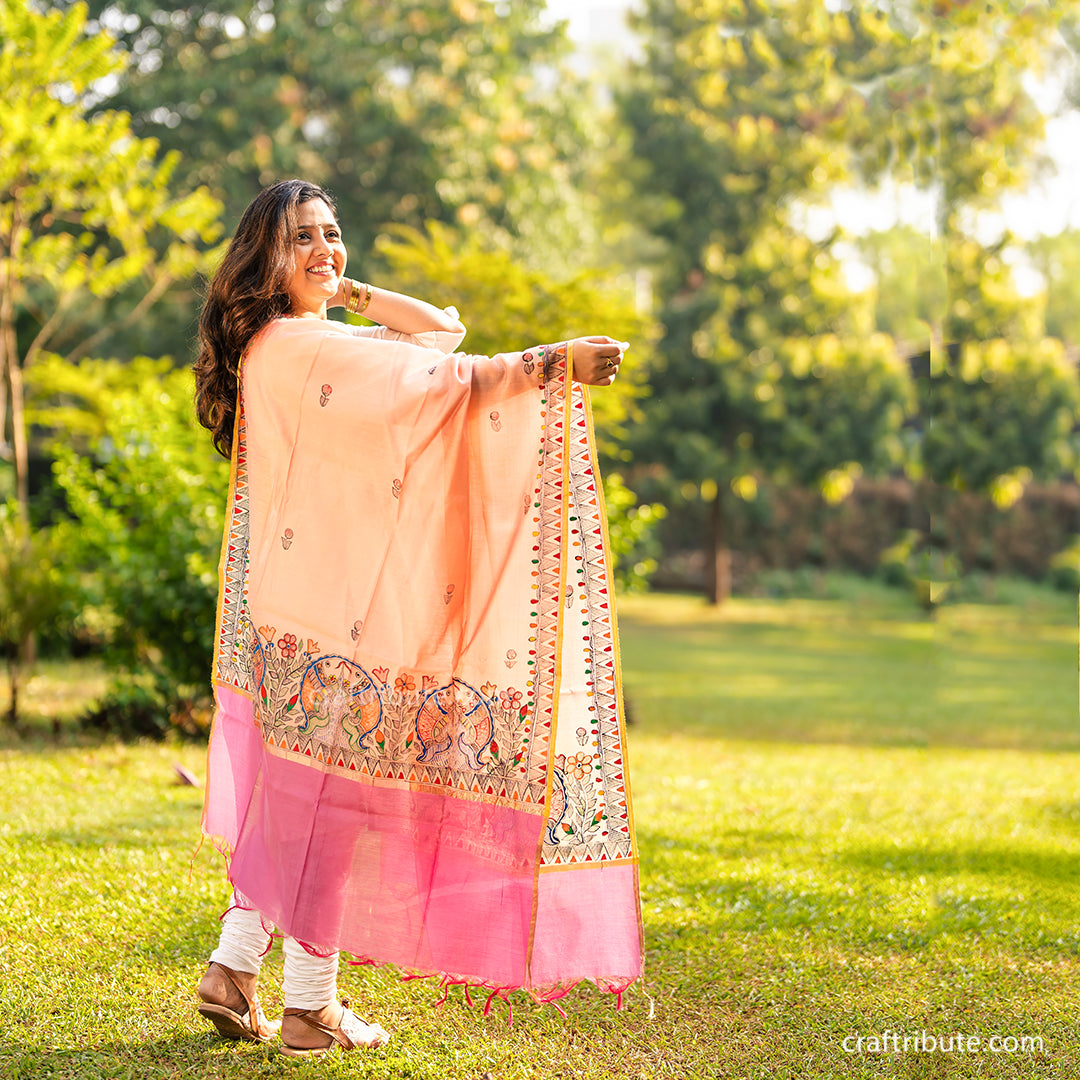 A girl wearing a hand painted madhubani dupatta with floral and fish design.