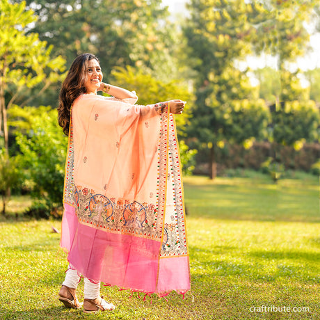 A girl wearing a hand painted madhubani dupatta with floral and fish design.