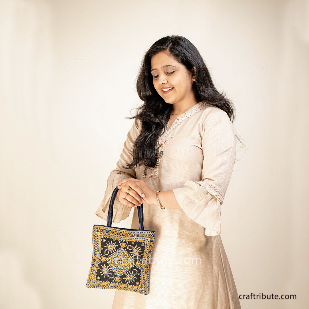 Lady carrying a handbag with Scorpio (Vicchi) design in Kutch 'Neran' Embroidery style, in attractive Black & Gold combination