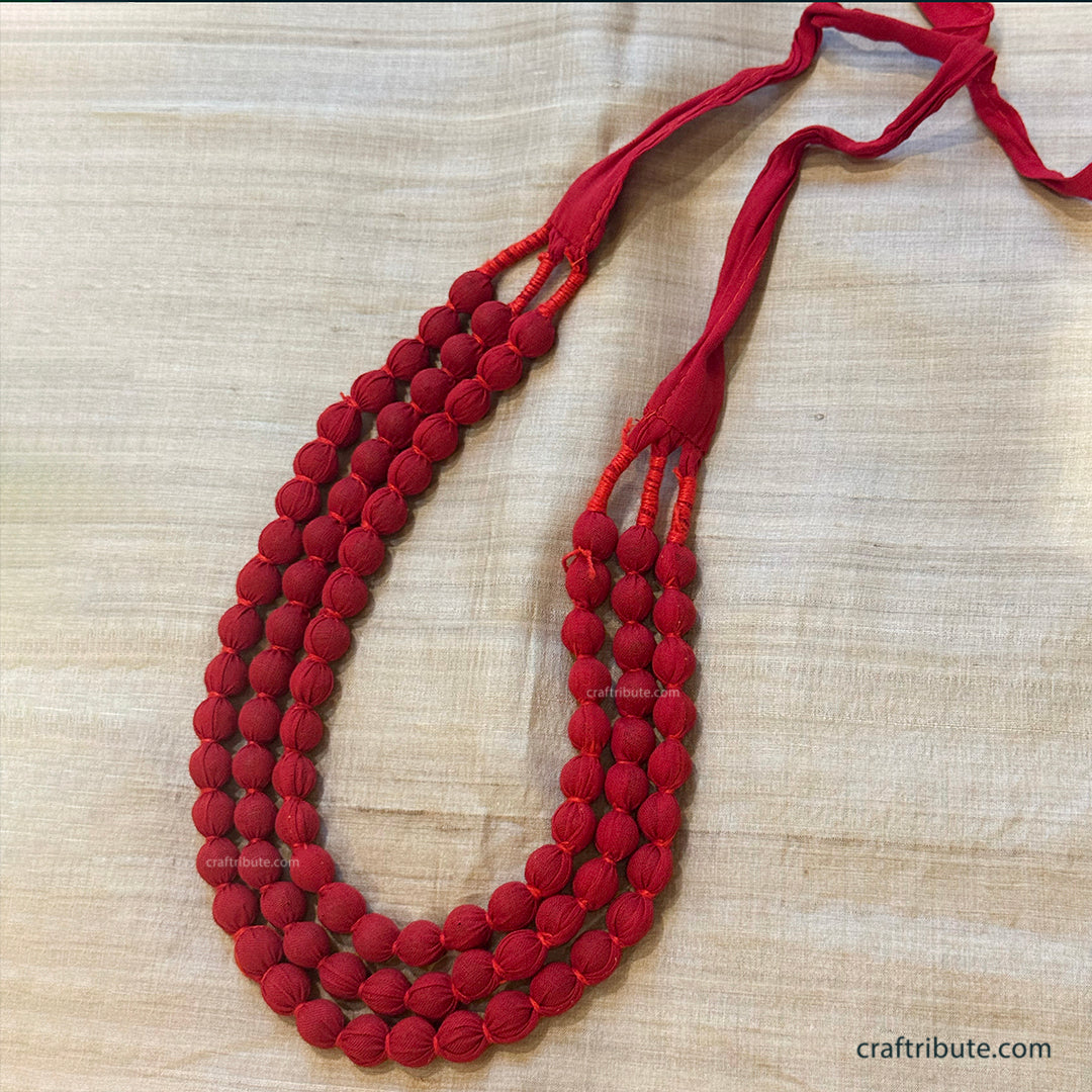 Red beaded necklace on a tussar silk background