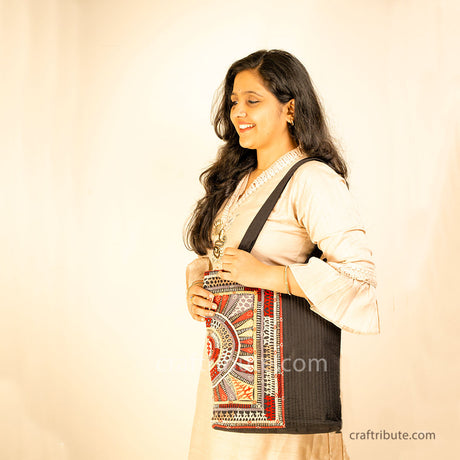 Girl carrying a black tote bag with Khudi Seba Kutch Embroidery with red & grey design