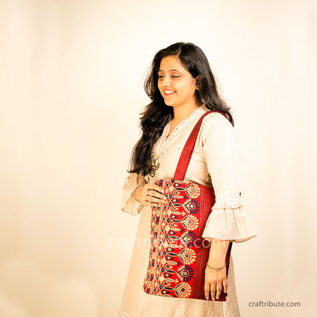Model flaunting a red tote bag with Ahir Kutch hand embroidery symbolising grandeur through its floral design in Black, Grey & Gold