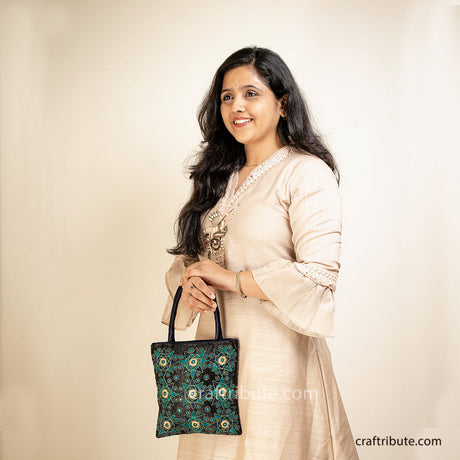 Girl holding a black hand bag showcasing Pakko Kutch Embroidery with 9 Stars design in attractive Green & silver combination