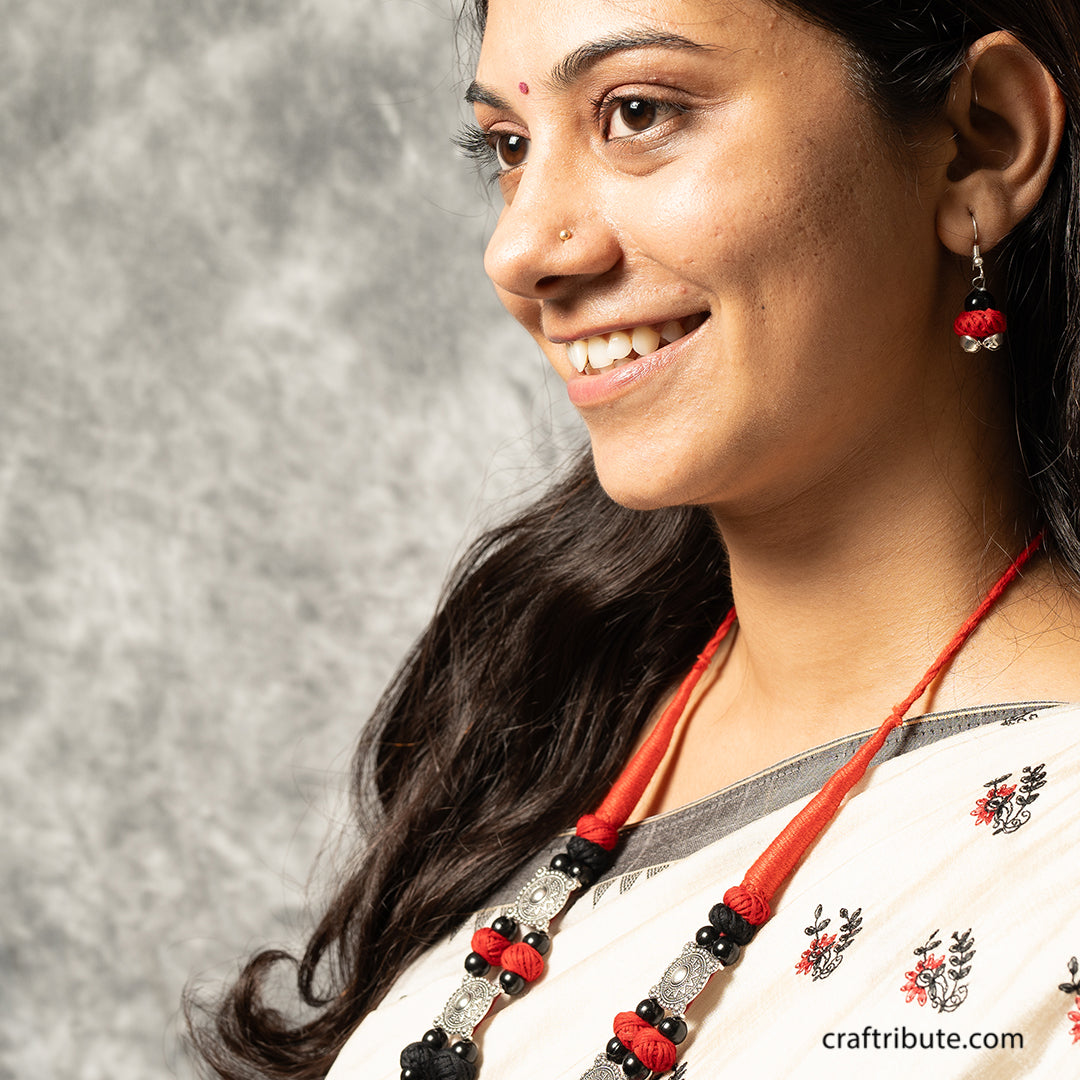 A lady wearing a decorative necklace and atractive earrings with red and black beads