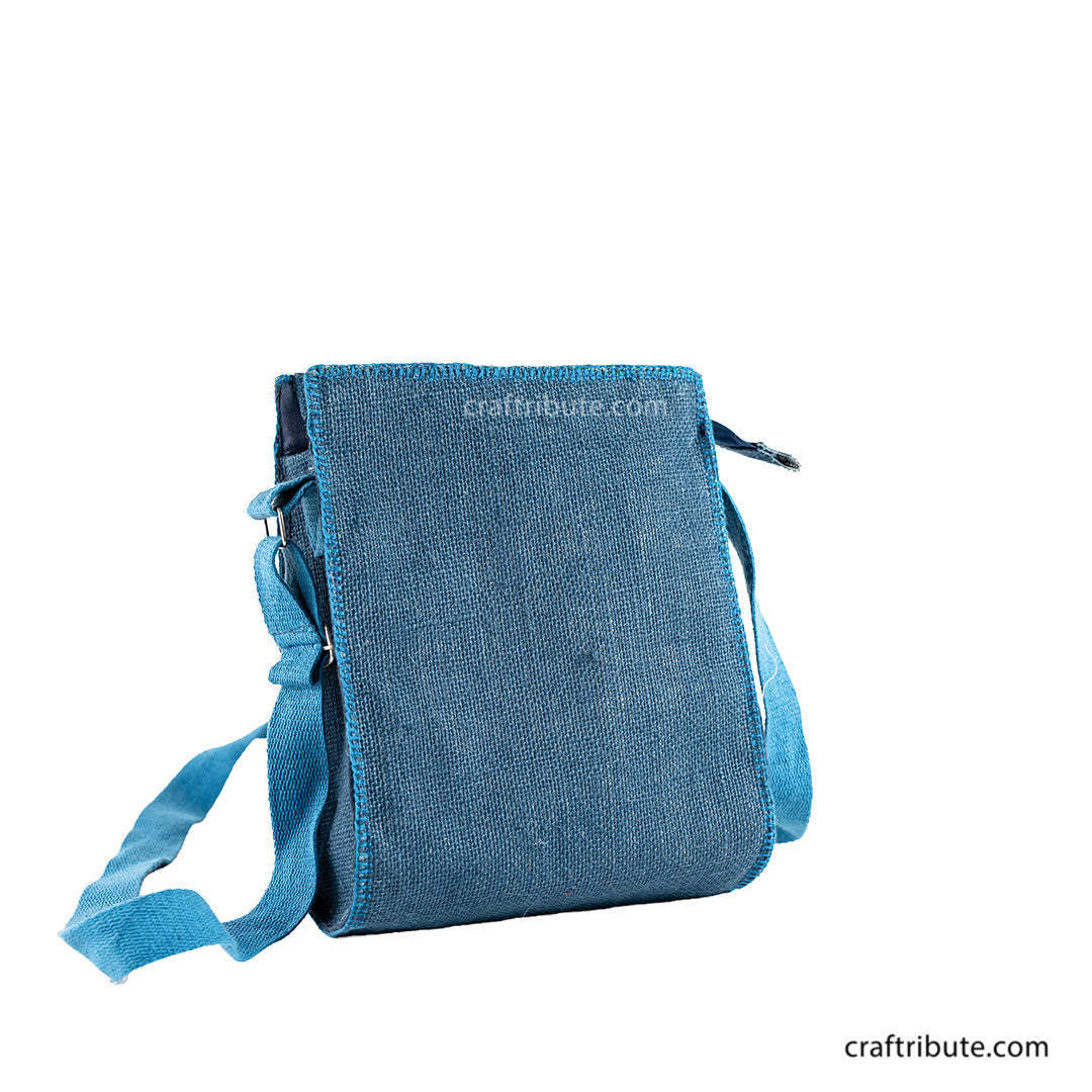 Back side of a hand embroidered blue jute sling bag with light blue & white crochet flowers