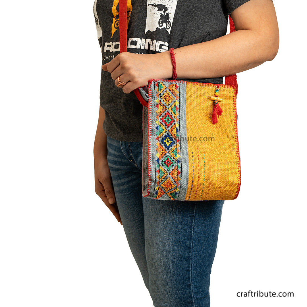 Model carrying a hand embroidered Yellow & Grey jute sling bag with red belt