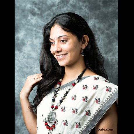 A lady wearing a beautiful necklace with a silver pendant with red and & black beads, and black birds with matching earrings