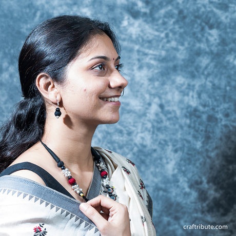 A lady wearing a beautiful necklace with matching black bead earrings
