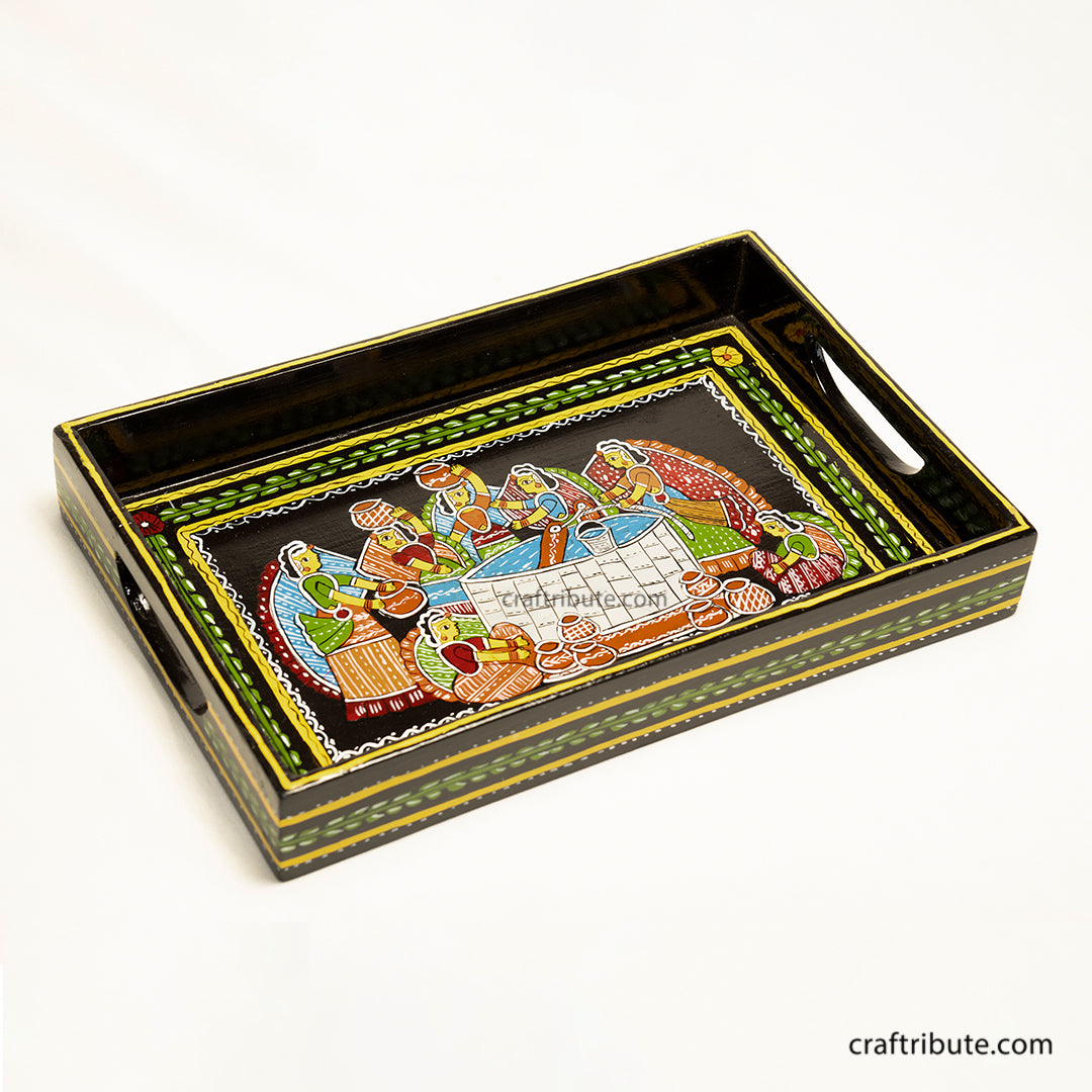 Wooden Serving Tray hand painted by women artisans from Bihar, depicting viollage women gathered around the well to draw water. Painted in vibrant colours on a black background