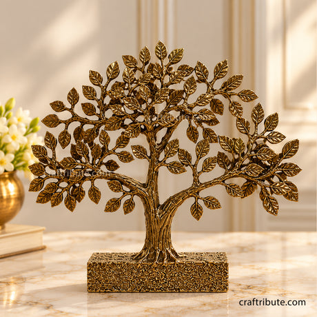 Handcrafted antique gold brass Bodhi tree sculpture with intricately detailed leaves, a textured trunk, and a decorative rectangular base, displayed on an elegant marble tabletop.