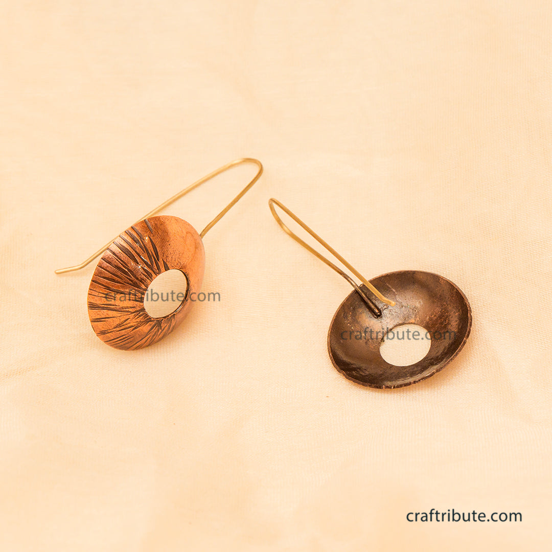 Two handmade oval drop earrings displayed on a warm beige textured background. One earring highlights the front side, and the other highlights the back side