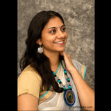 A lady wearing a silver earrings and necklace with cotton beads and silver pendants