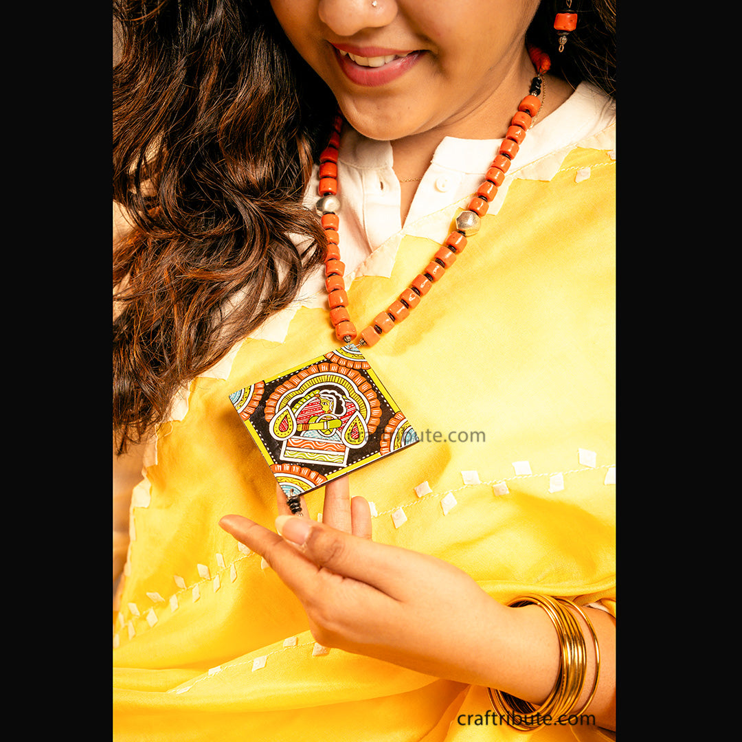 Close up of hand painted wooden pendant in traditional Tikuli Art