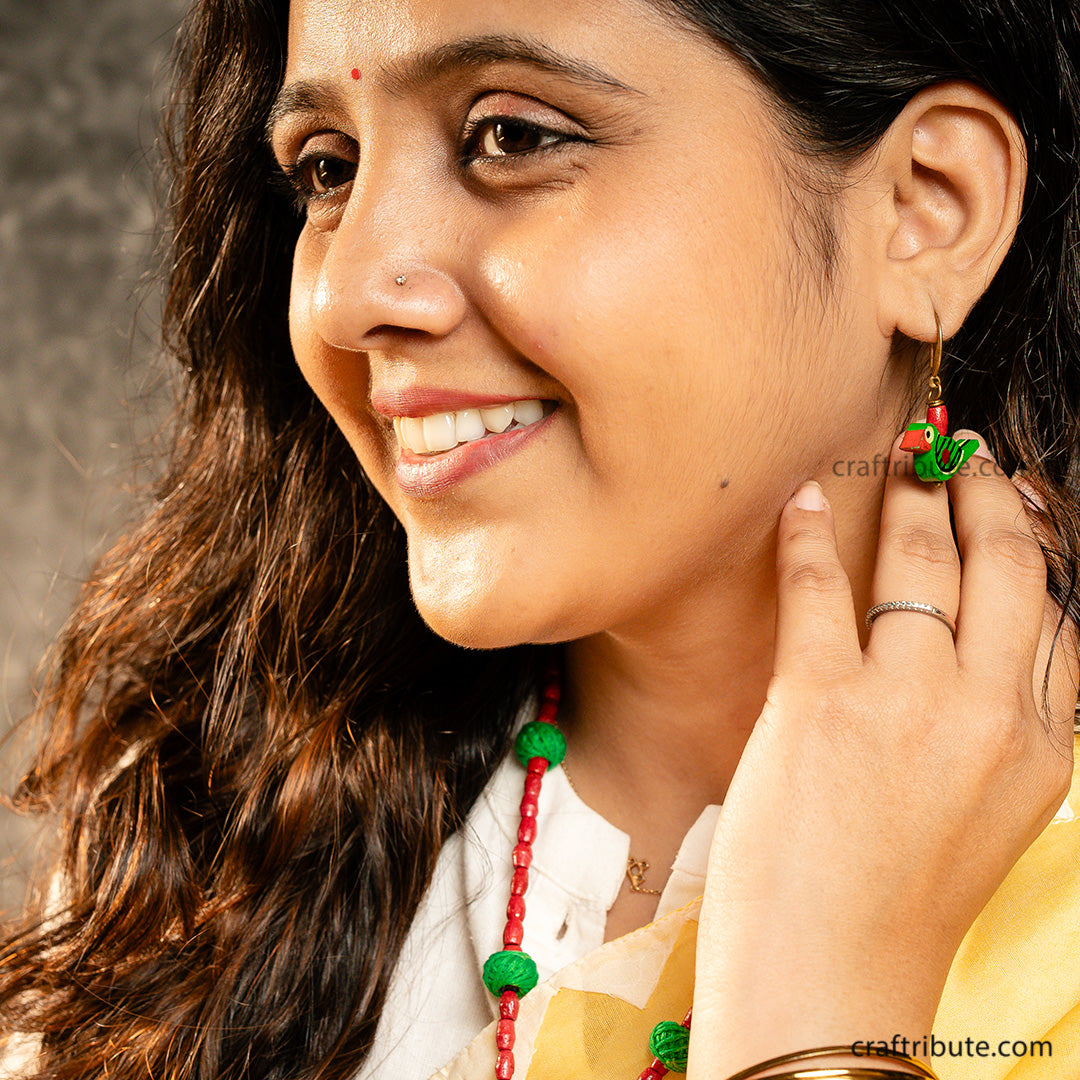 Close up of Green bird shaped wooden earrings with red bead