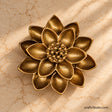 Handcrafted antique brass lotus flower décor with intricately textured layered petals and a detailed centre, photographed from above on a warm cream marble surface.