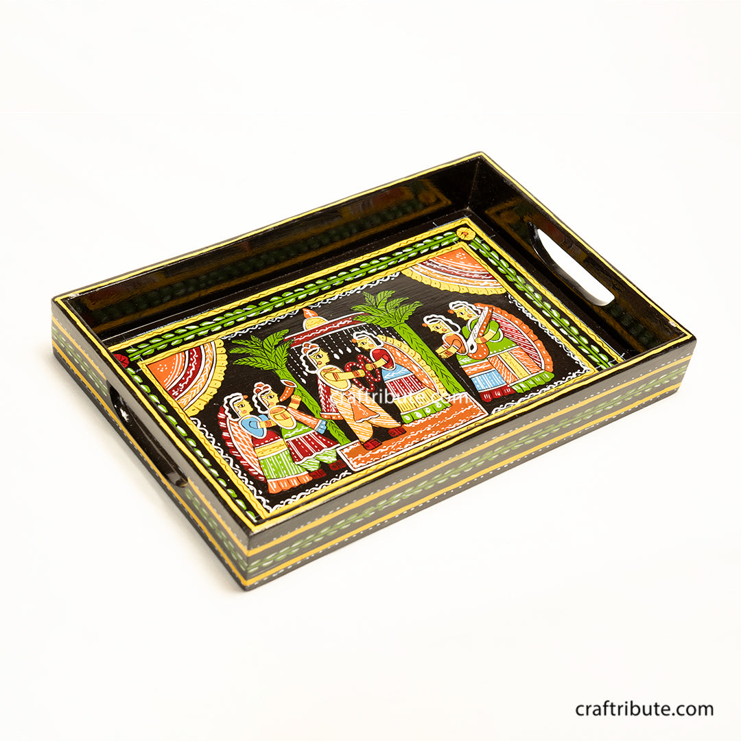An indian wedding scene hand painted on a decorative wooden serving tray. Intricate design and vibrant colours on black surface give it a very festive look.