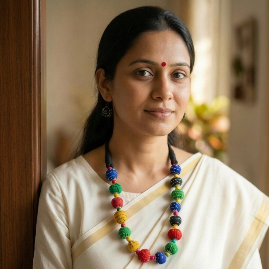 Woman wearing a colorful necklace and white saree indoors