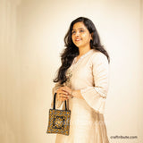 Girl demonstrating a Pakko Kutch Hand embroidered bag with Shining Star design in classic black & gold combination