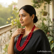 Woman wearing a red necklace with a blurred outdoor background