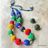 Colorful beaded necklace and earrings on a textured fabric background