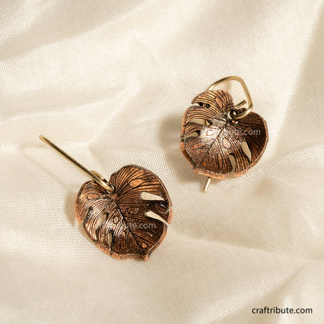 Copper leaf-shaped earrings with intricate texture inspired by Monstera Leaves. Curved inward 