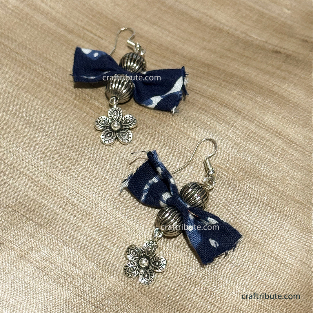 Upcycled indigo fabric butterfly earrings with silver accessories on a beige tussar silk background