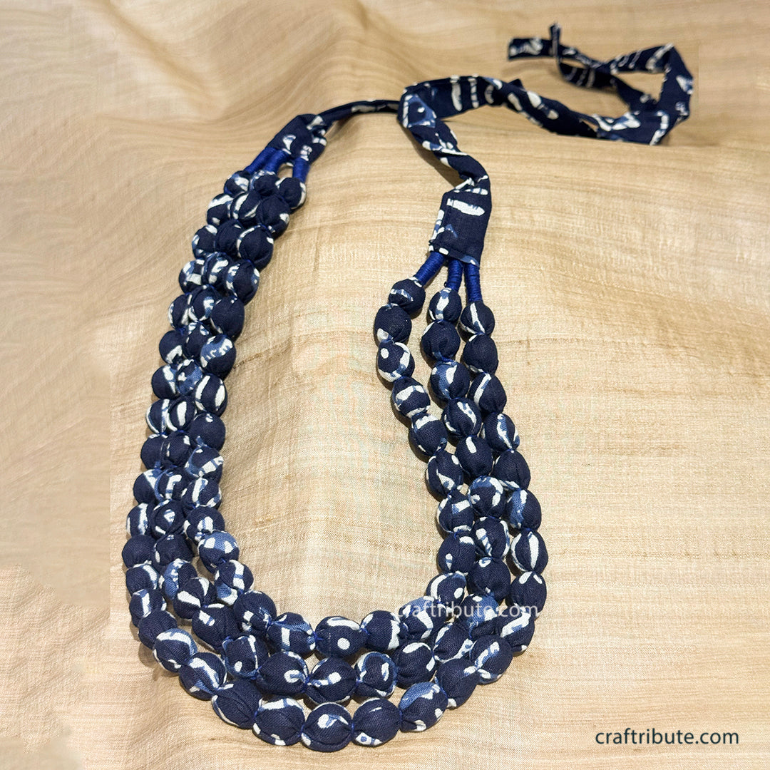Upcycled indigo fabric 3 layer beaded necklace on a beige tussar silk background