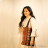 Lady showcasing a tote bag with Ahir embroidery symbolising abundance through its floral design in Red & Gold