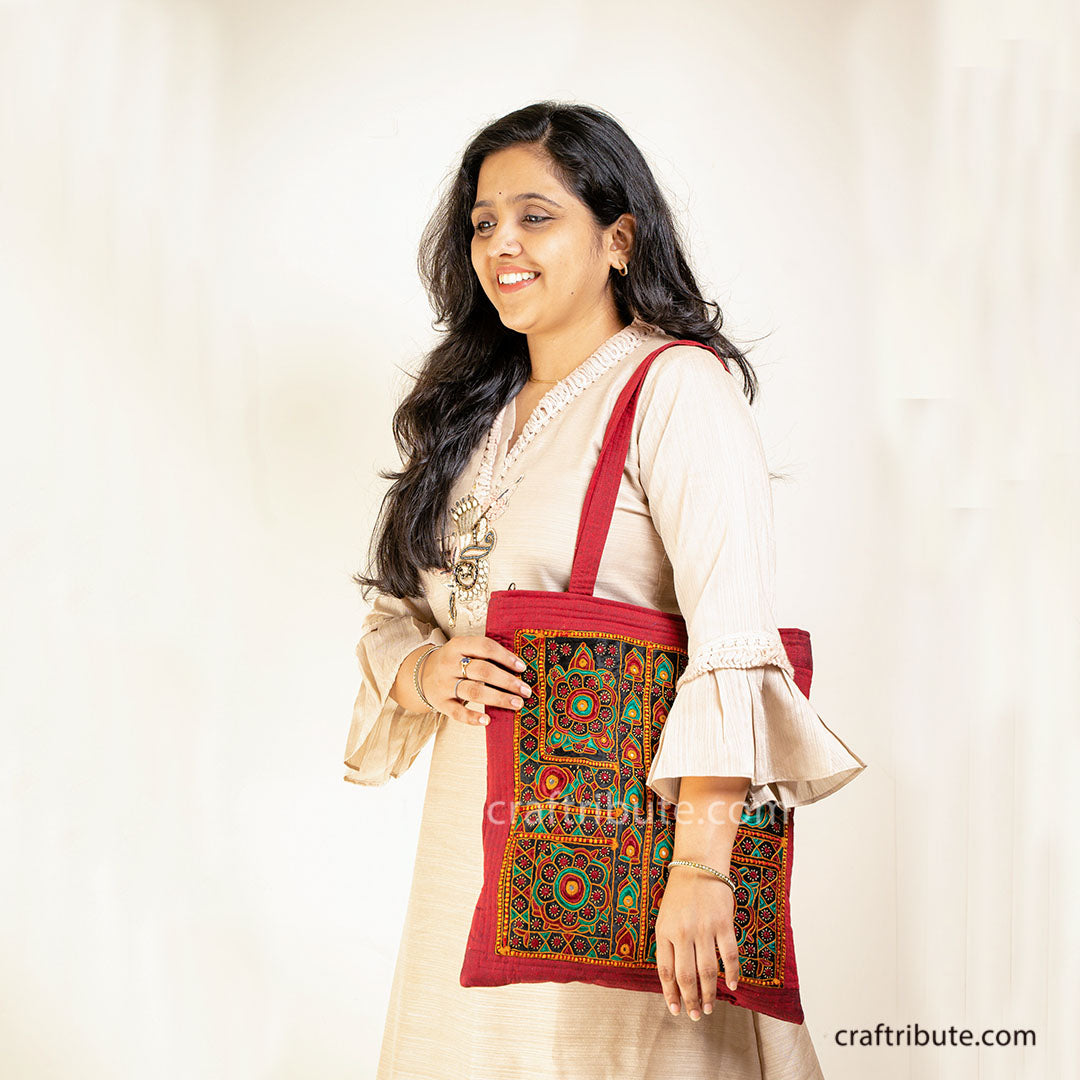 Lady with a tote bag embellished with Sindhi Memon style of Kutch hand embroidery in Red & Green colours