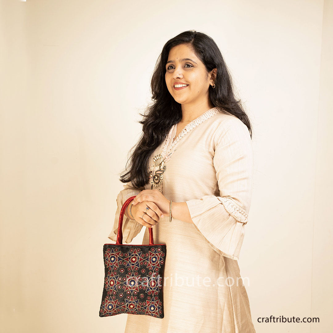 Girl displaying a hand bag showcasing Pakko Kutch Embroidery with 9 Stars design in attractive red & black combination 