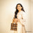 Girl flaunting a black hand bag showcasing Pakko Kutch Embroidery with 9 Stars design in attractive Orange & Gold  colour combination