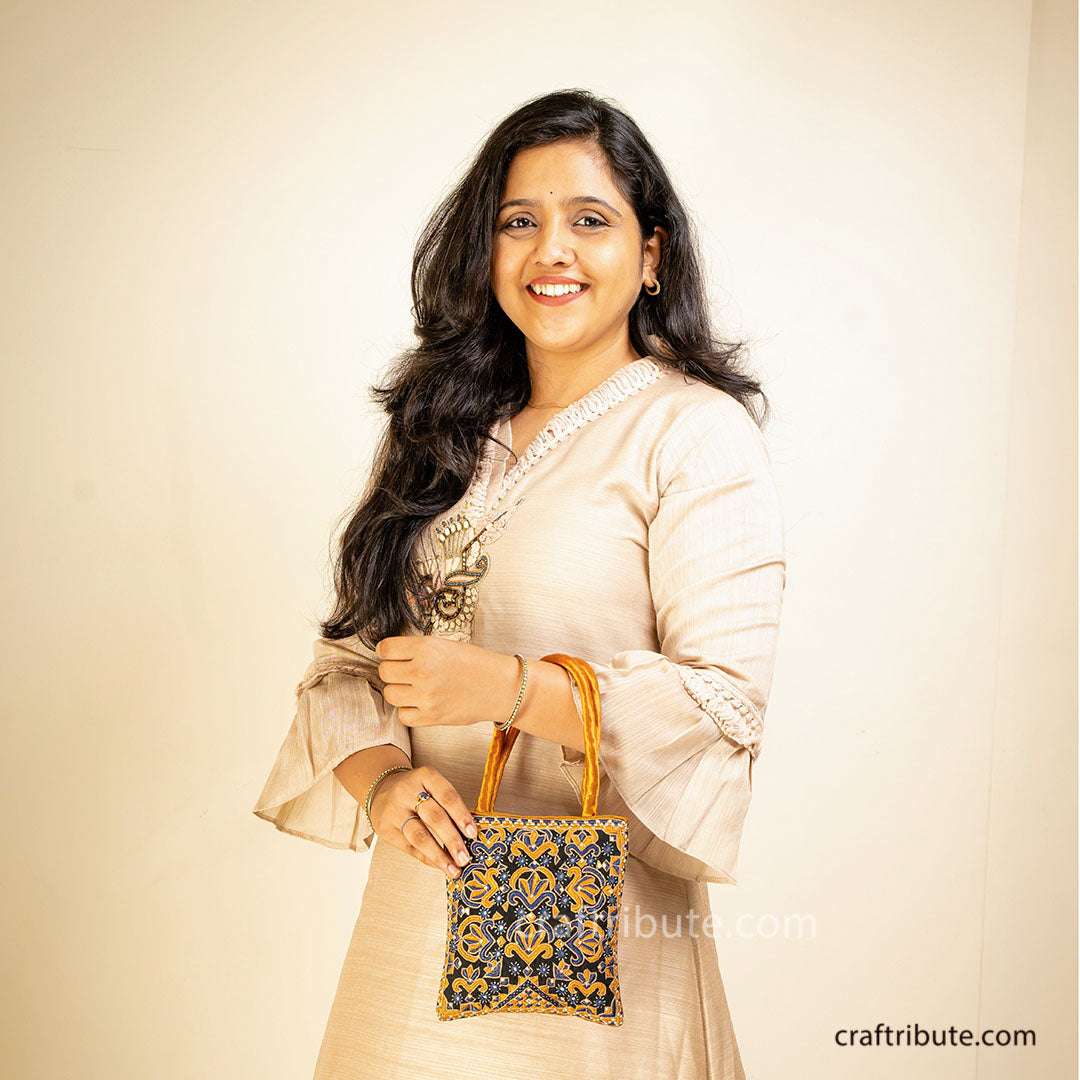 Pakko (Kutch Embroidery) handbag with floral design in beautiful gold and blue colours carried by a girl