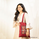 Girl holding a Tote bag with intricate Sindhi Memon embroidery in red & gold colours
