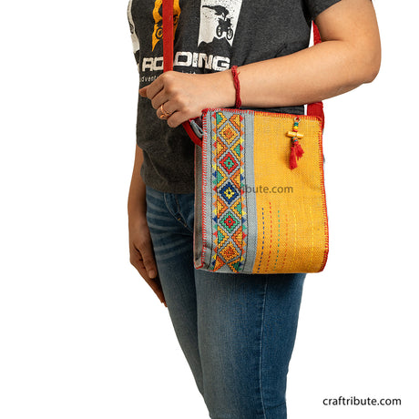 Model carrying a hand embroidered Yellow & Grey jute sling bag with red belt