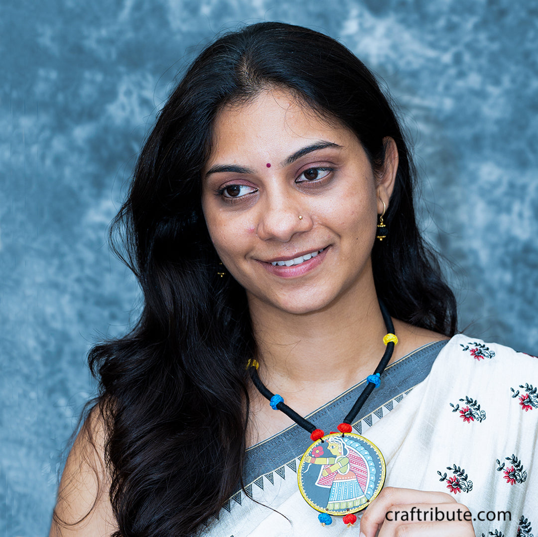 A lady flaunting a black thread necklace with colourful beads, with a beautiful hand-painted Tikuli Art pendant  