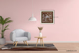 A beautiful framed square Warli painting hangs on a light pink wall in a modern living room mockup with a gray armchair, side table, and hanging lamp.
