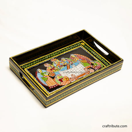Tikuli Art hand painted wooden tray depicting women gathered around the well to draw water. Painted in attractive colours  on a black background
